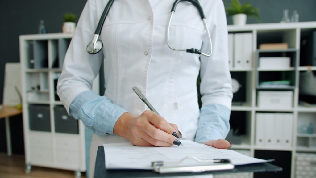 Médico escrevendo em prancheta no consultório