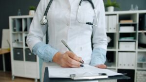 Médico escrevendo em prancheta no consultório